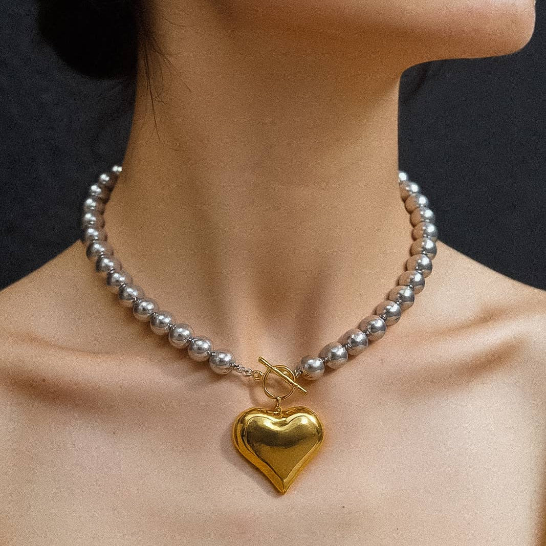 Necklace with a gold heart pendant worn by a person against a dark background