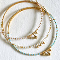 Gold and turquoise beaded necklaces on a white background
