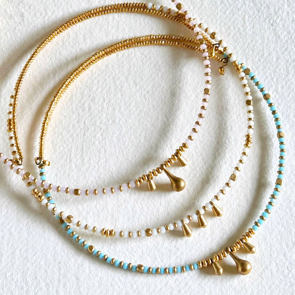 Gold and turquoise beaded necklaces on a white background
