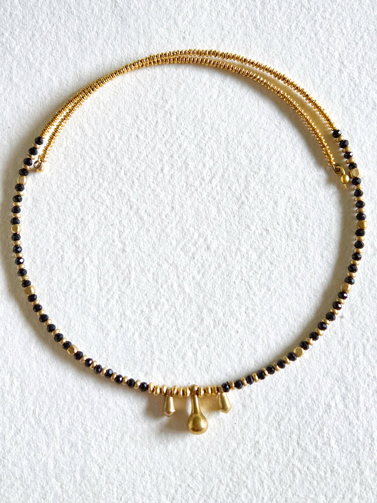 Gold and black beaded necklace on a white background