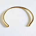 A minimalist style collar necklace, photographed on a textured white surface.